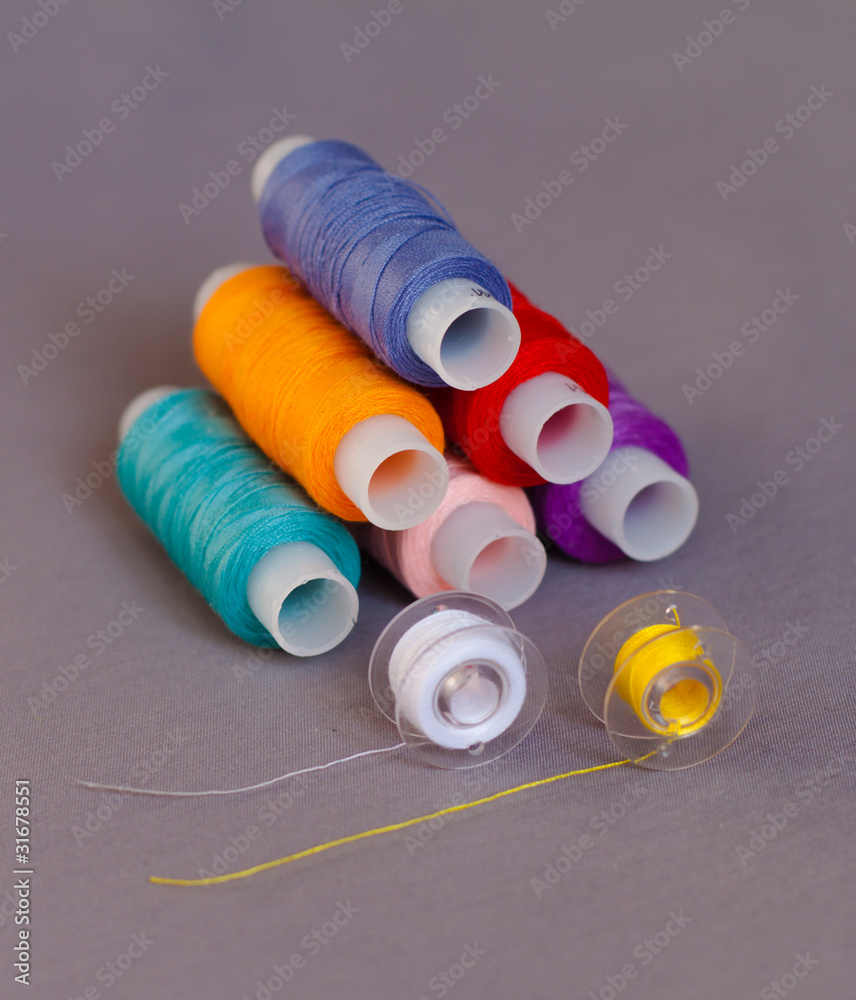 нитки и шпульки на сером фоне
