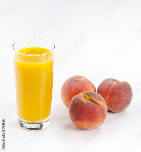 Glass with fresh peach juice near the peaches