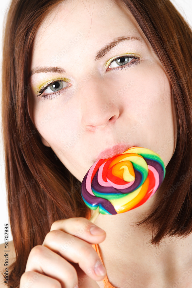 closeup of young brunette girl  eating big multicolored lollipop