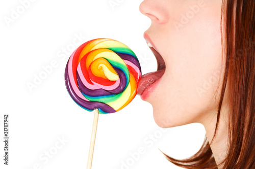closeup of young brunette girl licking big multicolored lollipo
