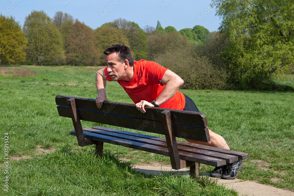 Fototapeta premium Runner doing pressups on a Park Bench