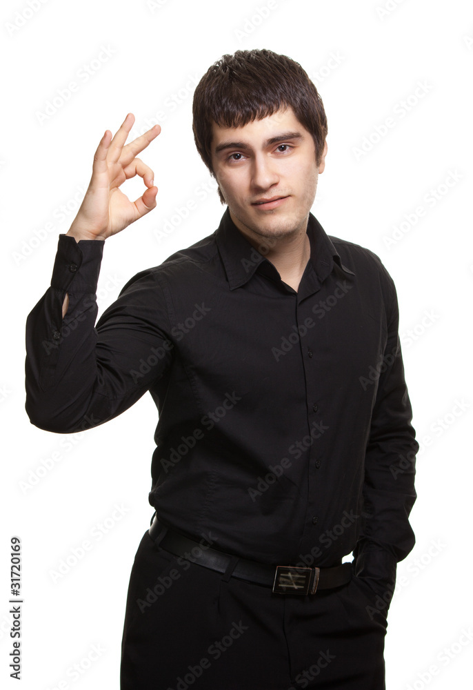Portrait of young man in black shirt gesturing ok sign against w Portrait of young man in black shirt gesturing ok sign against w