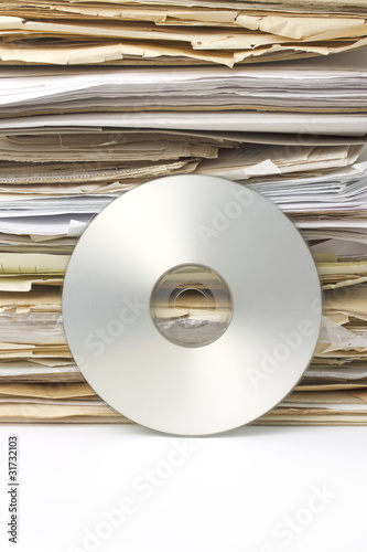 Stack of old paper files and  silver cd