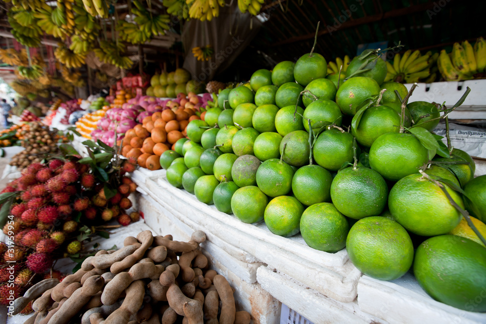 Naklejka premium Piles of Limes and Other Fruit in Cambodian Market