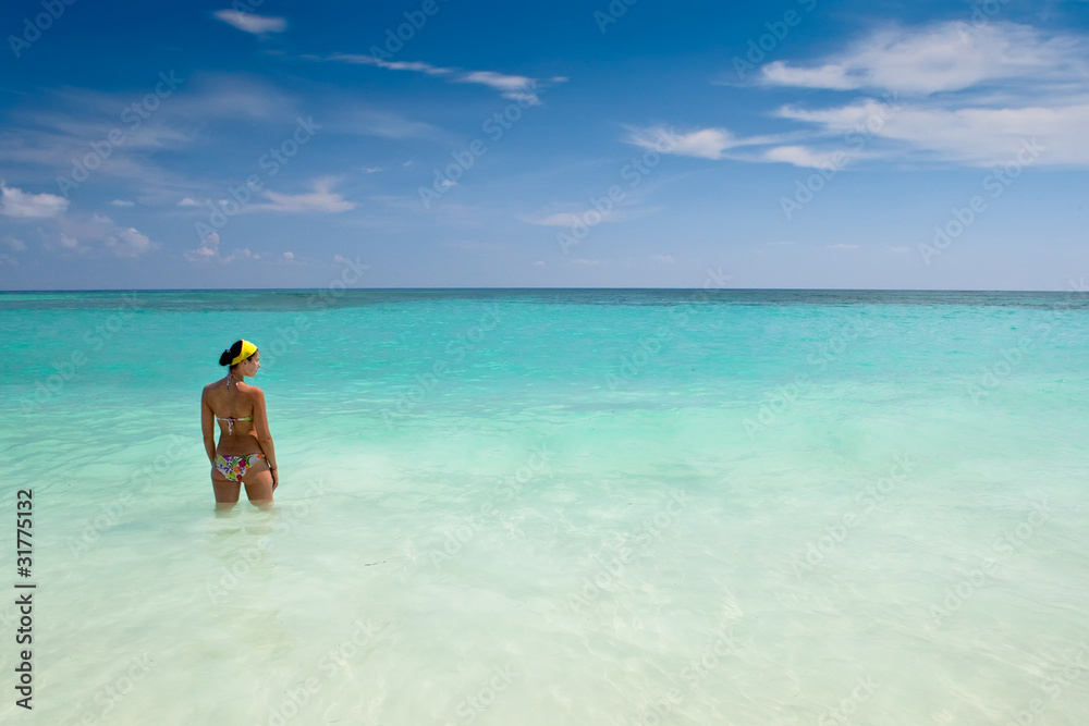 Tanned girls is standing in bright blue ocean Tanned girls is standing in bright blue ocean