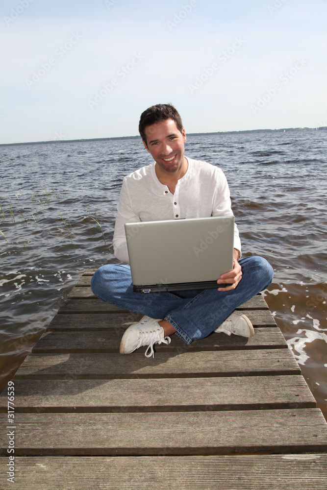 Man sitting on a pontoon with laptop computer