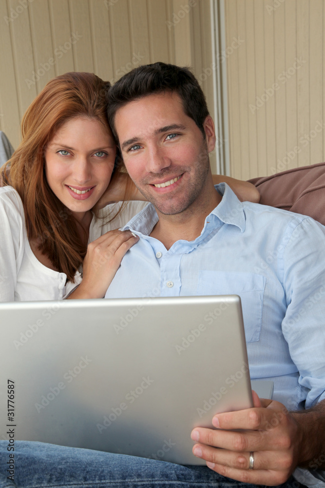 Couple sitting in couch with laptop computer Couple sitting in couch with laptop computer