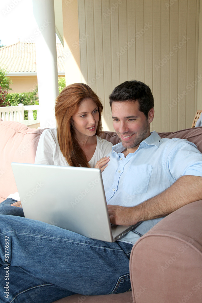 Couple sitting in couch with laptop computer Couple sitting in couch with laptop computer