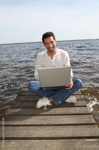 Man sitting on a pontoon with laptop computer