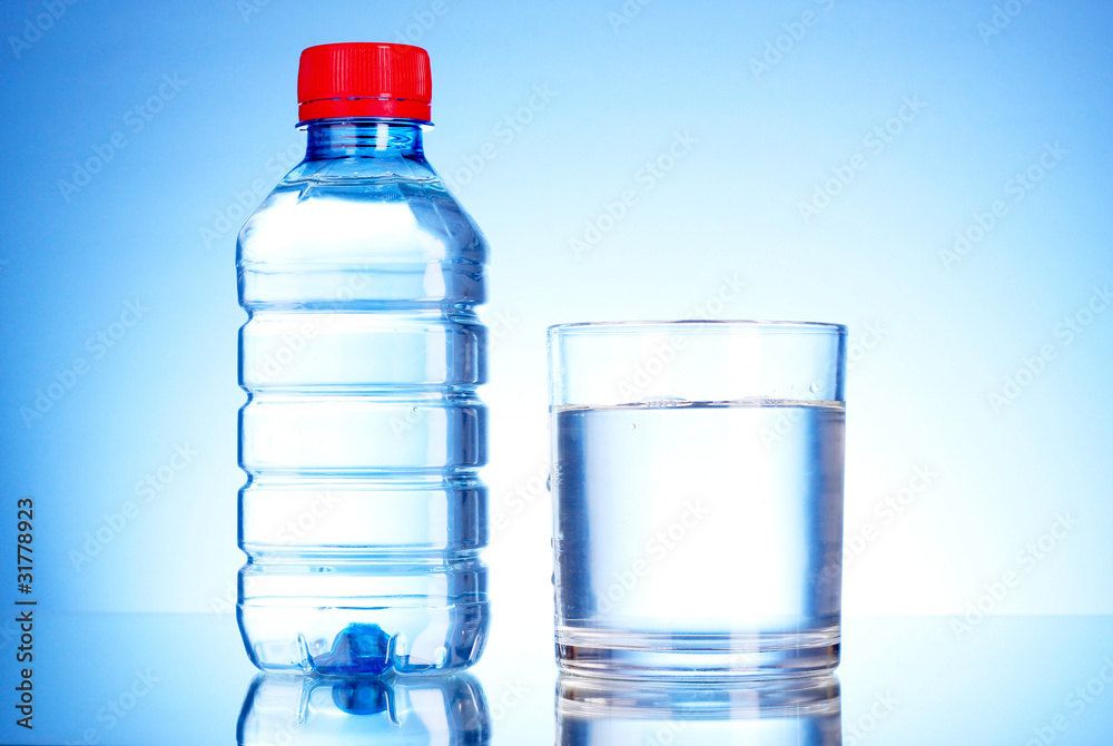 Bottle of water and glass on blue background