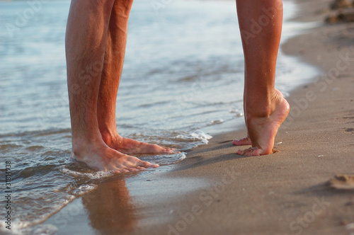 legs of kissing couple on beach