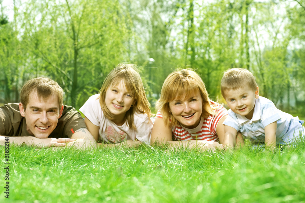 Happy Family outdoor lying on green grass Happy Family outdoor lying on green grass