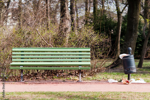 Parkbank mit überfülltem Mülleimer