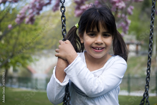 Young girl sitting on swing, smiling, portrait