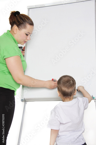 teacher and young boy next to white board photo