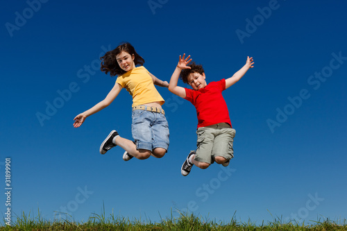 Girl and boy jumping, running against blue sky © Jacek Chabraszewski