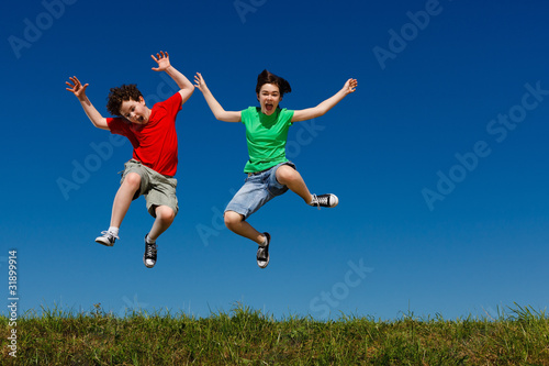Girl and boy jumping, running against blue sky © Jacek Chabraszewski