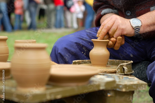 hands of a potter, creating an earthen jar on the circle © mariangarai
