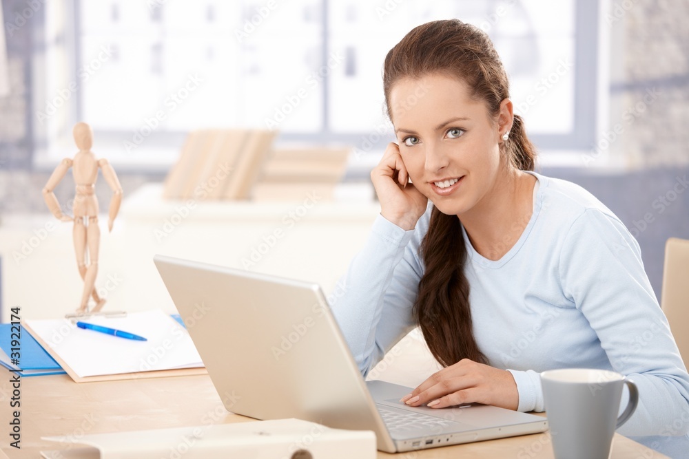 Young woman working on laptop in bright office Young woman working on laptop in bright office
