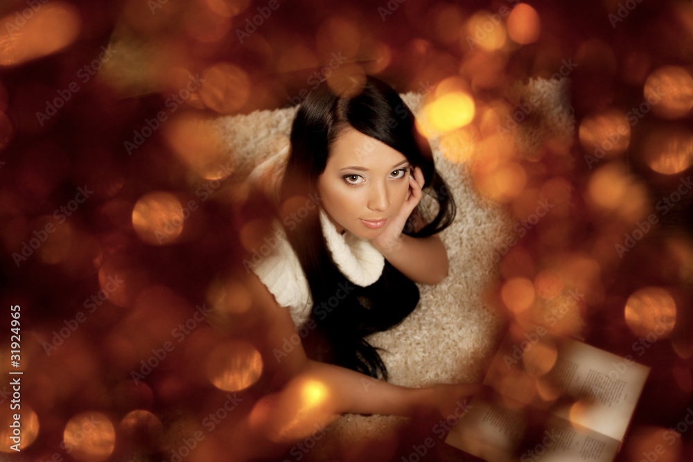 Girl lying near the fireplace and reads a book