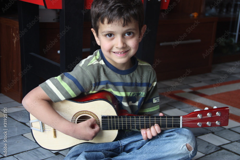 Foto Stock bambino che suona la chitarra Adobe Stock