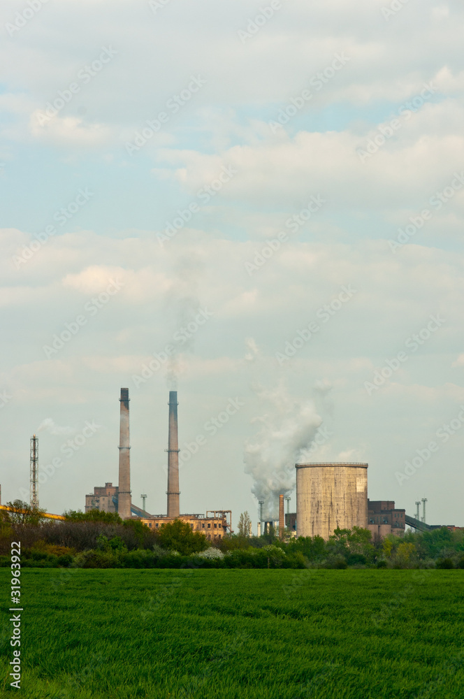 power plant with green grass and smoke rising