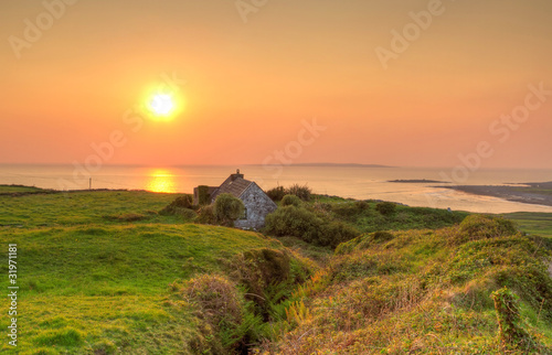 Irish cottage house near ocean at sunset
