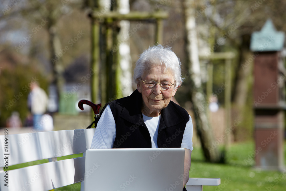 Nette alte Dame mit Laptop auf Bank 32 Nette alte Dame mit Laptop auf Bank 32