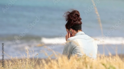 Mujer en la playa hablando por teléfono