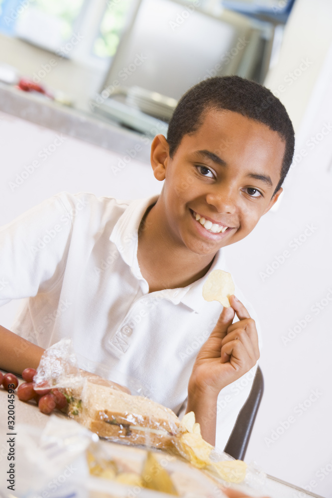 Schoolboy enjoying his lunch in a school cafeteria Schoolboy enjoying his lunch in a school cafeteria