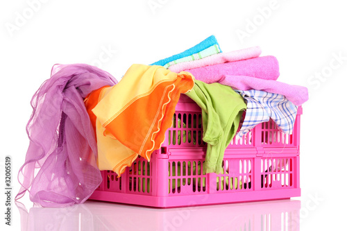 Bright clothes in a laundry basket on white background photo