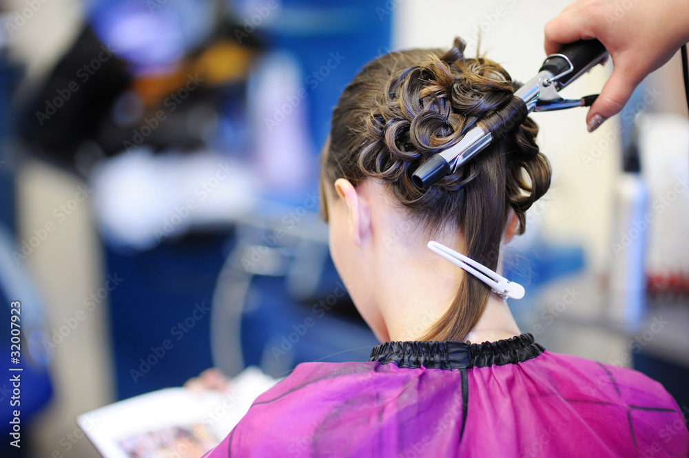 Naklejka premium Woman's stylist's hands making a fancy hairstyle