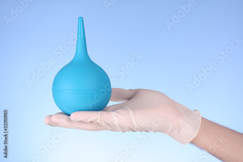 Small enema on hand with blue background photo