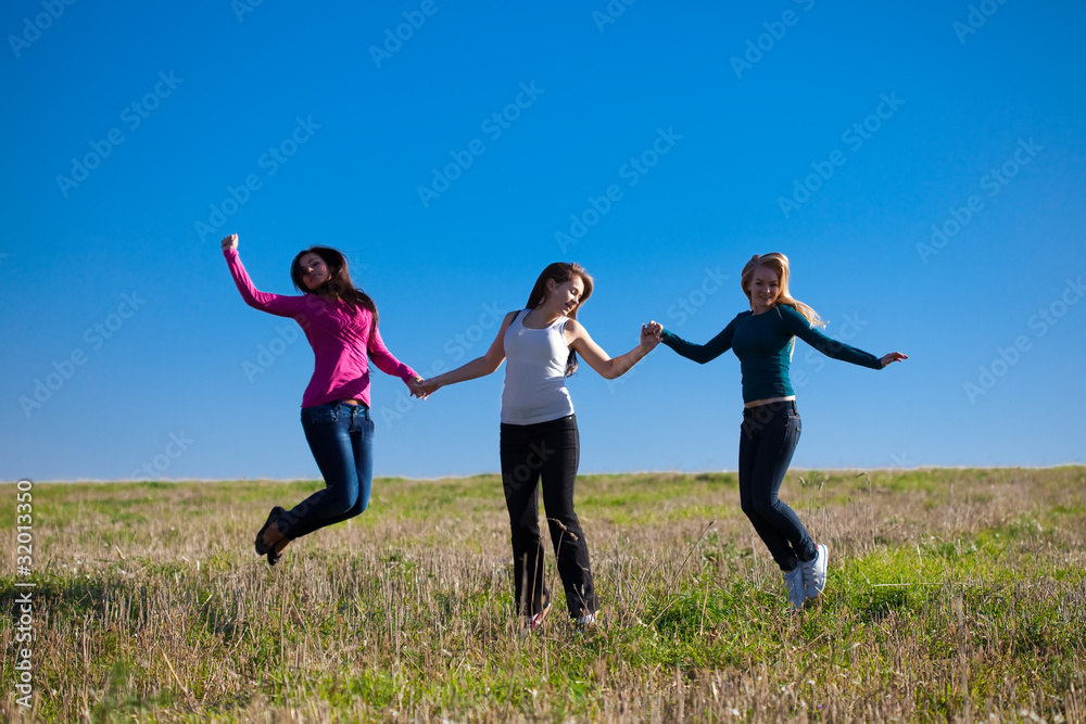 three young beautiful woman jumping into the field against the s three young beautiful woman jumping into the field against the s