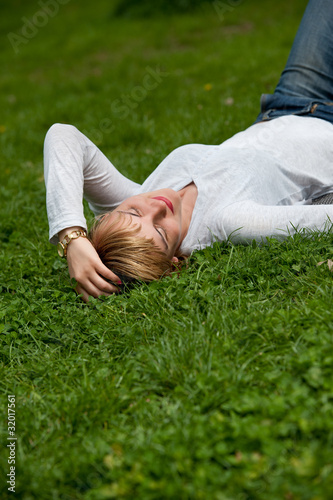 Beautiful healthy Young Woman lying on the green grass © lpstudio