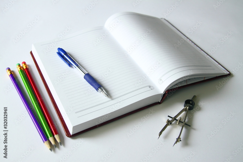 An open book with a pencil and a pen on a white background An open book with a pencil and a pen on a white background