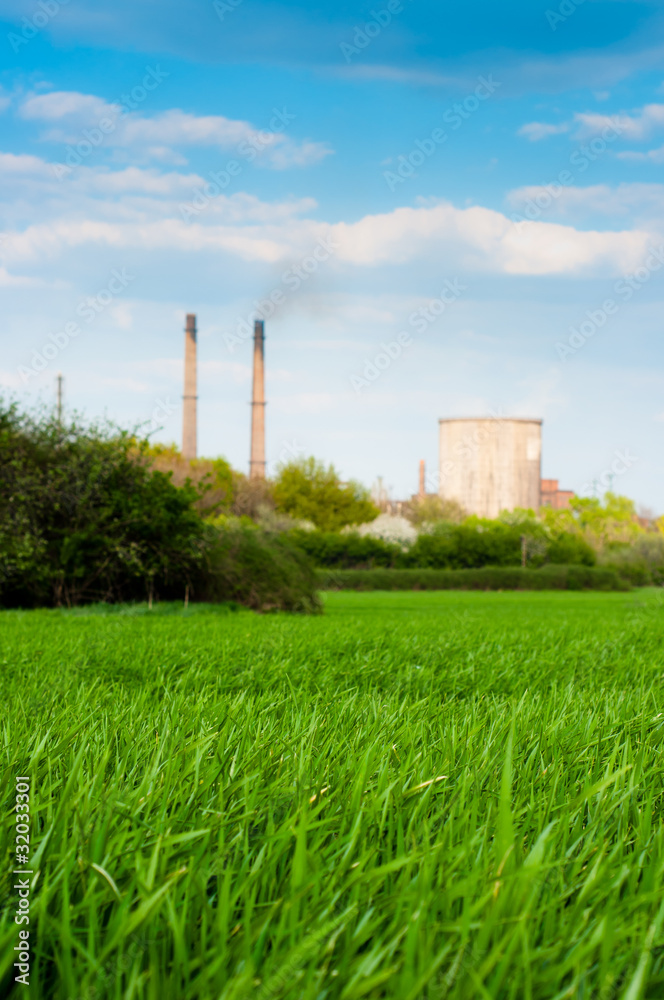 Fresh green grass with nuclear power plant and blue sky