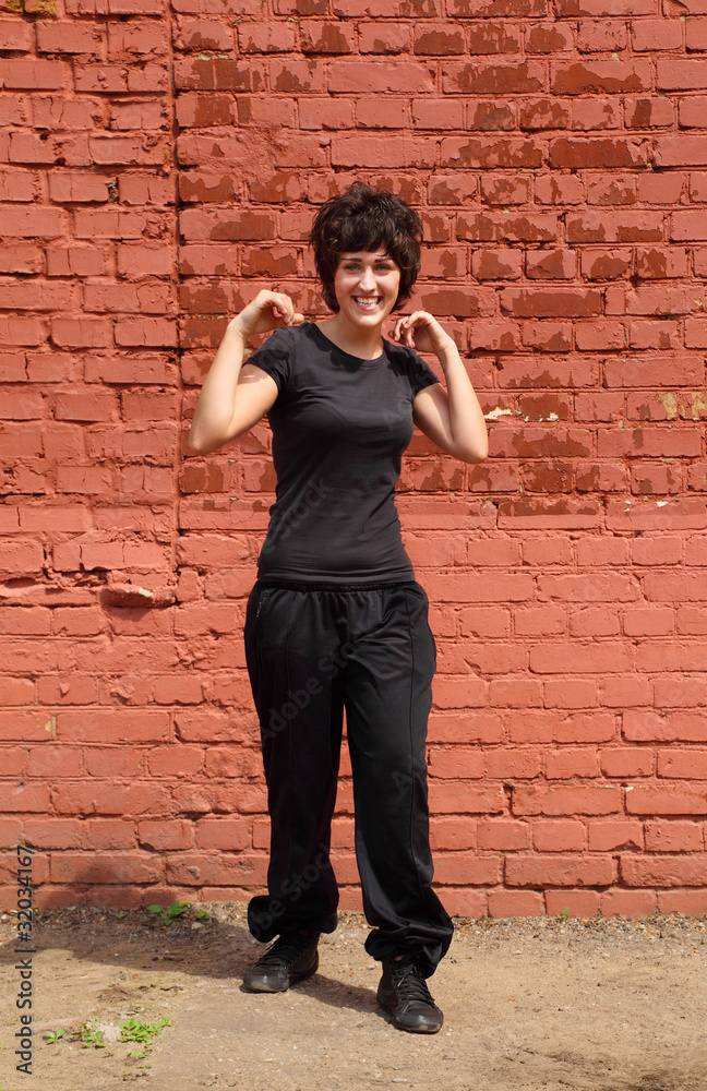 Girl in black clothes make gymnastics on background of wall Girl in black clothes make gymnastics on background of wall