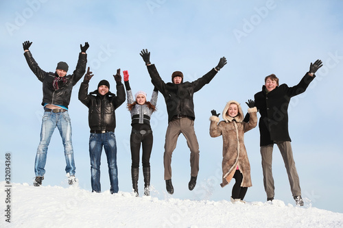 Students jump in winter on to snow and lift hands upwards