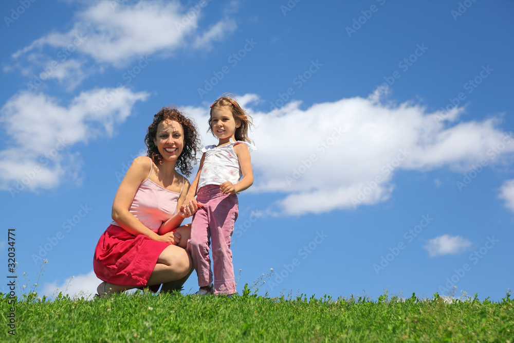 Mother squatting alongside with daughter holds it for hand Mother squatting alongside with daughter holds it for hand