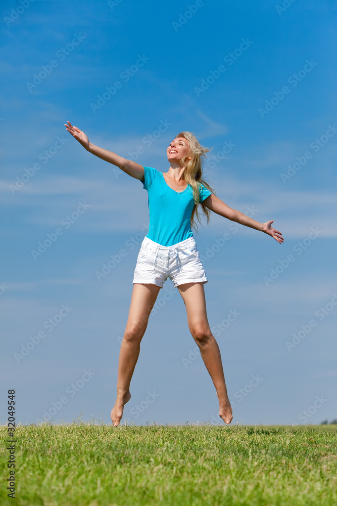 The happy young woman jumps in the field The happy young woman jumps in the field