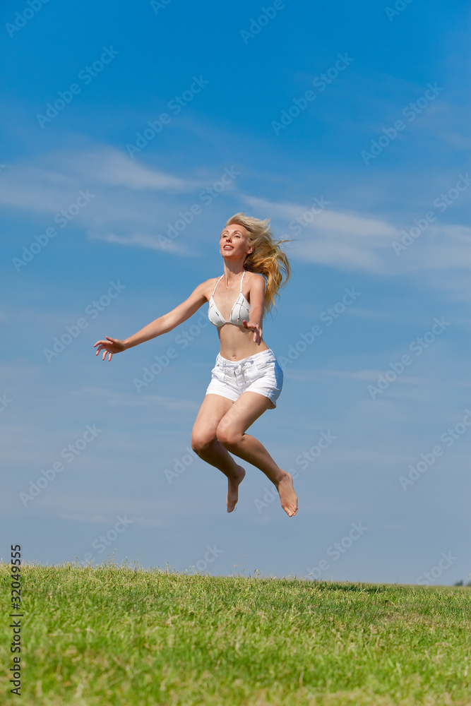The happy young woman jumps in the field The happy young woman jumps in the field