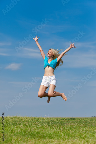 The happy young woman jumps in the field