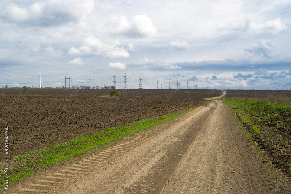 Country road between the spring fields in Ukraine.