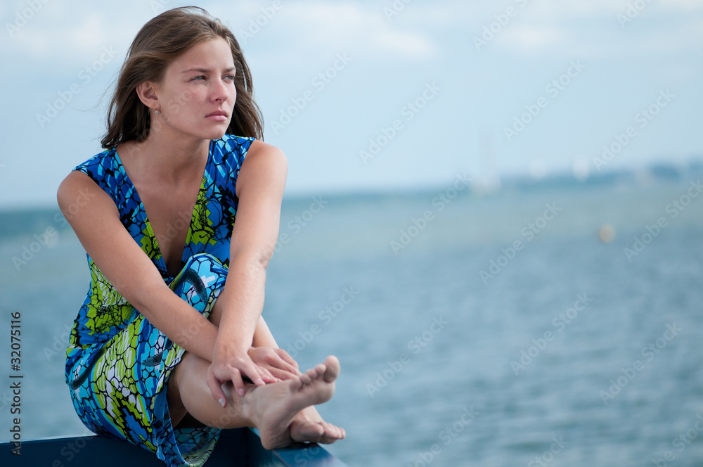 sad woman sitting over sea at summer day