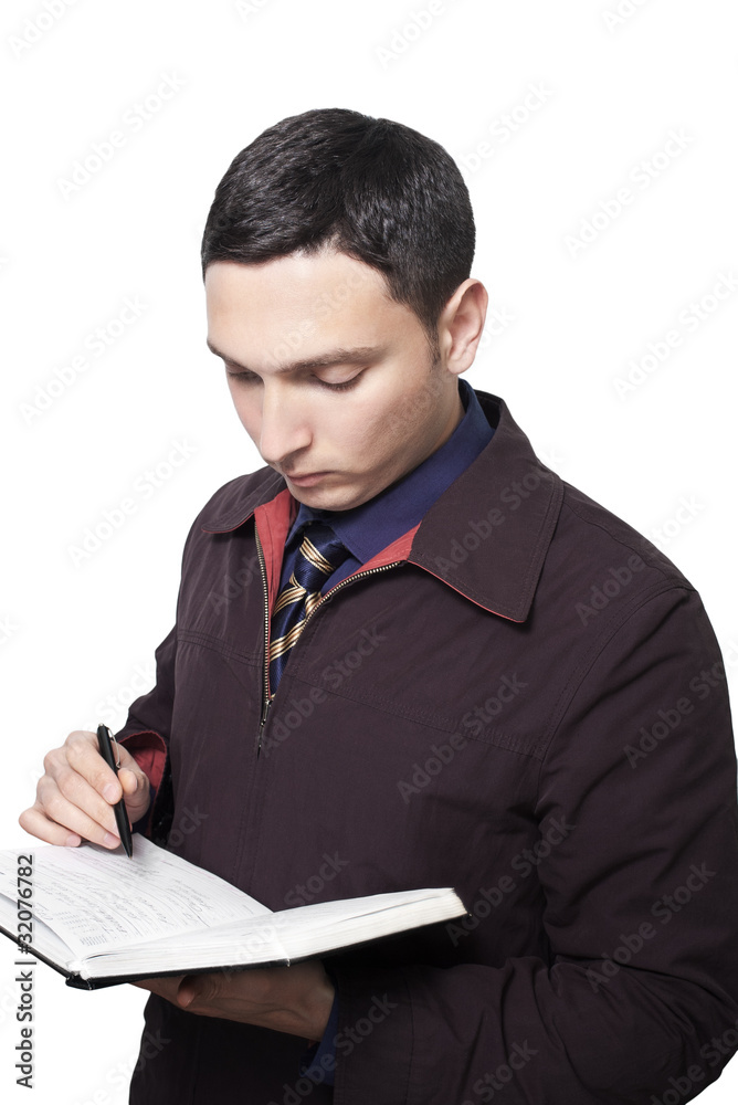 man in dark jacket and tie looking down and writing in planner man in dark jacket and tie looking down and writing in planner
