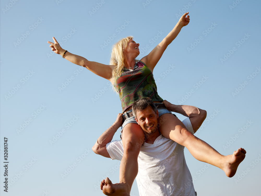 Smiling young man giving piggyback ride to his woman outdoors Smiling young man giving piggyback ride to his woman outdoors