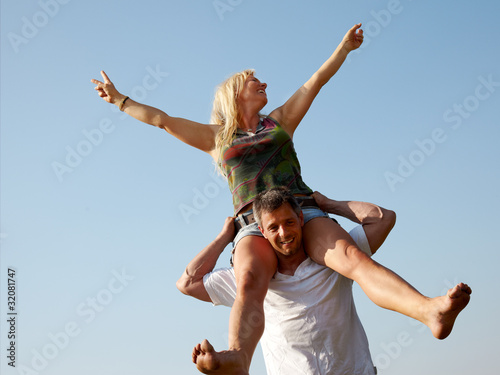 Smiling young man giving piggyback ride to his woman outdoors