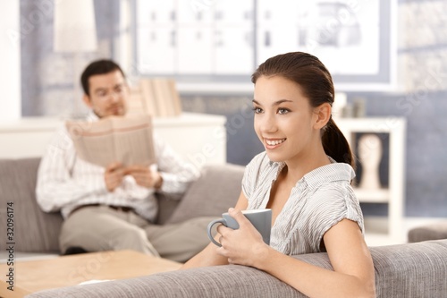 Young couple sitting on sofa at home smiling