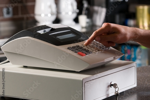 Closeup of a cashier's hand ringing cash register.